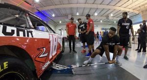 A member of the Pit Crew Combine lifts a car up with the jack during a mock pit stop.