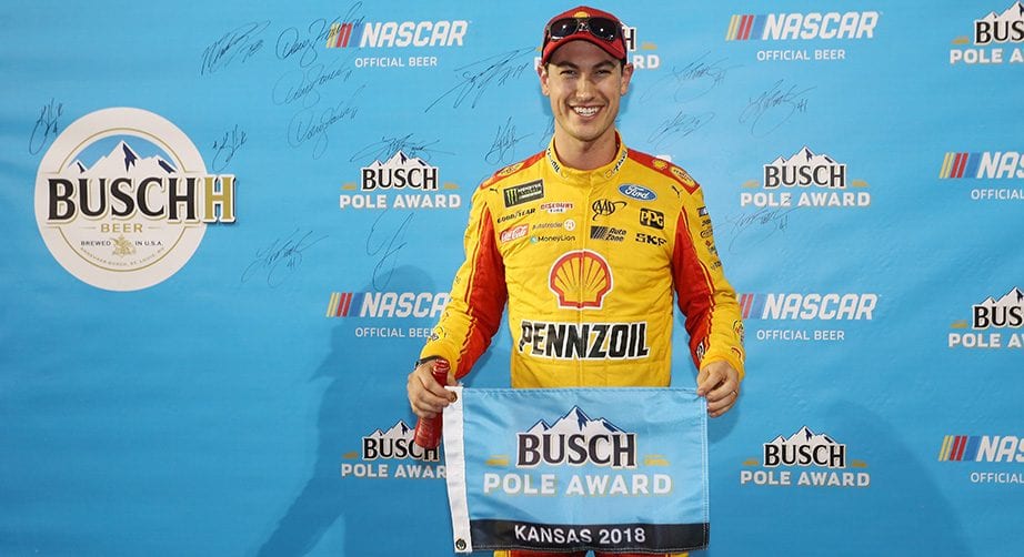 Joey Logano holds the banner for winning the Busch Pole Award at Kansas Speedway.