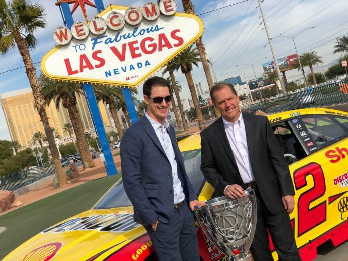 Joey Logano and crew chief Todd Gordon pose with the championship trophy and the No. 22 car by the famous Welcome to Las Vegas sign.