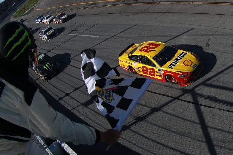 Joey Logano races under the checkered flag to win the Monster Energy NASCAR Cup Series' GEICO 500 at Talladega Superspeedway.