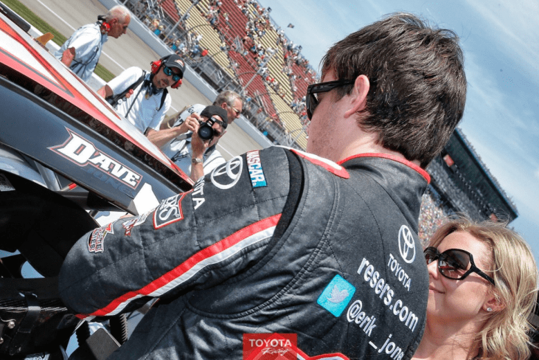 Erik Jones places a sticker with his father's name above his car's door as his mother looks on