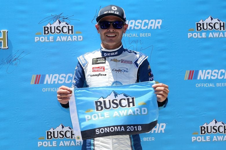 Kyle Larson holds up the Busch Pole Award flag.