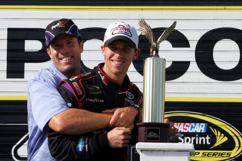 LONG POND, PA - AUGUST 03: Denny Hamlin (R), driver of the #11 FedEx Express Toyota, and team owner J.D. Gibbs pose in victory lane after winning the NASCAR Sprint Cup Series Sunoco Red Cross Pennsylvania 500 at the Pocono Raceway on August 3, 2009 in Long Pond, Pennsylvania. (Photo by Chris Trotman/Getty Images for NASCAR) | Getty Images