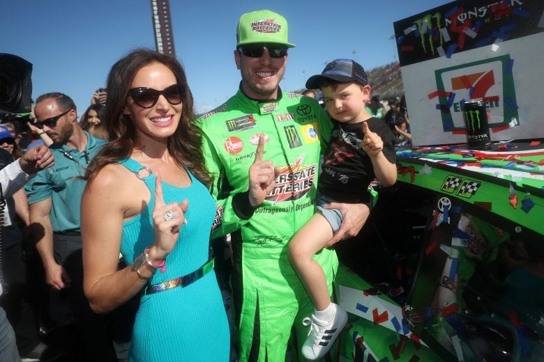 FONTANA, CA - MARCH 17: Kyle Busch, driver of the #18 Interstate Batteries Toyota, celebrates by placing the Winner's Sticker on his car with his wife Samantha and son Brexton after winning the Monster Energy NASCAR Cup Series Auto Club 400 and winning his 200th NASCAR race at Auto Club Speedway on March 17, 2019 in Fontana, California. (Photo by Chris Graythen/Getty Images) | Getty Images