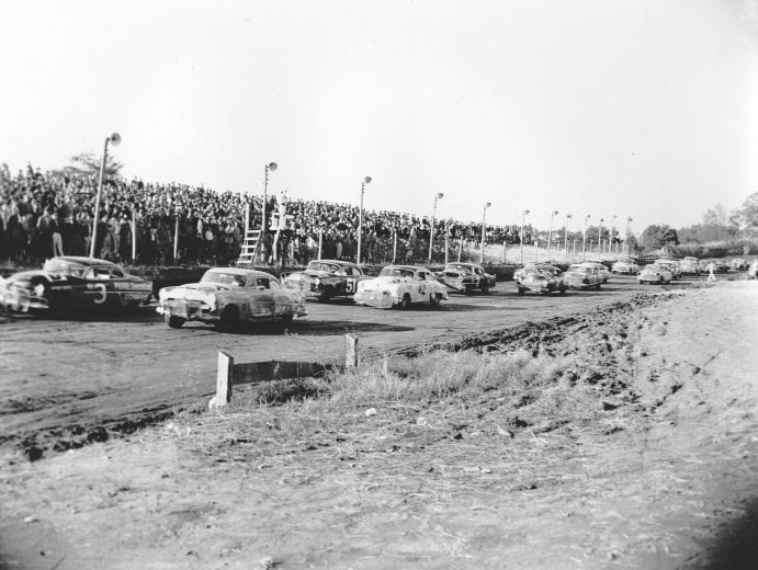 NORTH WILKESBORO, NC - OCTOBER 24, 1954:  The starter gives the field the one-lap-to-go signal prior to the start of the final NASCAR Cup race of the season that was held at North Wilkesboro Speedway.  Cars pictured include the Hudson Hornets of Dick Rathman (No. 3) and Herb Thomas (No. 92), the Oldsmobile of Gober Sosebee (No. 51), the Chrysler of Lee Petty (No. 42) and the Cadillac of Gwyn Staley (No. 7). (Photo by ISC Images & Archives via Getty Images)
