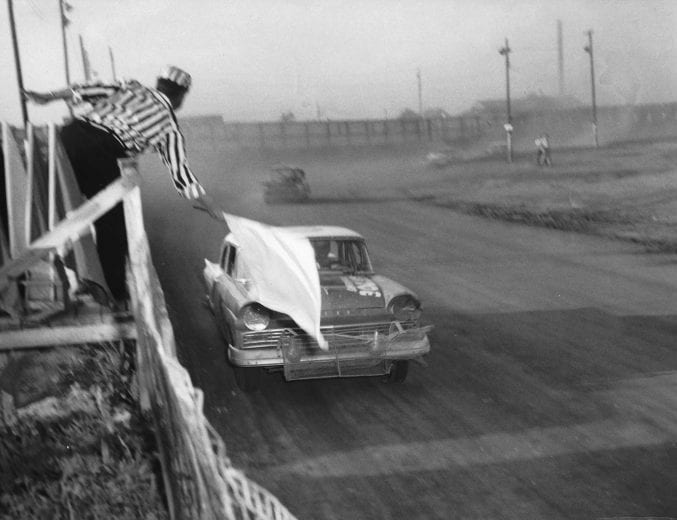 GREENSBORO, NC — April 28, 1957:  Race leader Paul Goldsmith takes the white flag during a NASCAR Cup race at the Greensboro Fairgrounds.  Goldsmith went on to victory in the race, driving Smokey Yunick’s 1957 Ford, one of four wins Goldsmith had on the Cup circuit during the year.  (Photo by ISC Images & Archives via Getty Images)