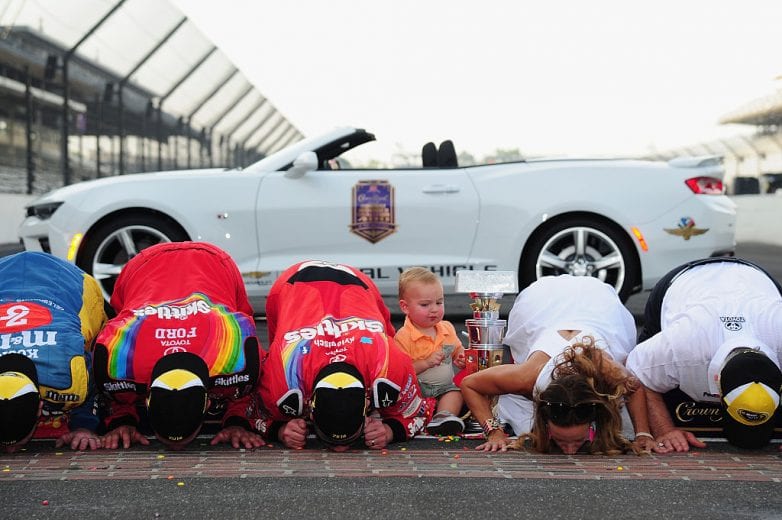 INDIANAPOLIS, IN - JULY 24: Kyle Busch, driver of the #18 Skittles Toyota, kisses the bricks with his wife, Samantha, after winning the NASCAR Sprint Cup Series Crown Royal Presents the Combat Wounded Coalition 400 at Indianapolis Motor Speedway on July 24, 2016 in Indianapolis, Indiana. (Photo by Jeff Curry/NASCAR via Getty Images)