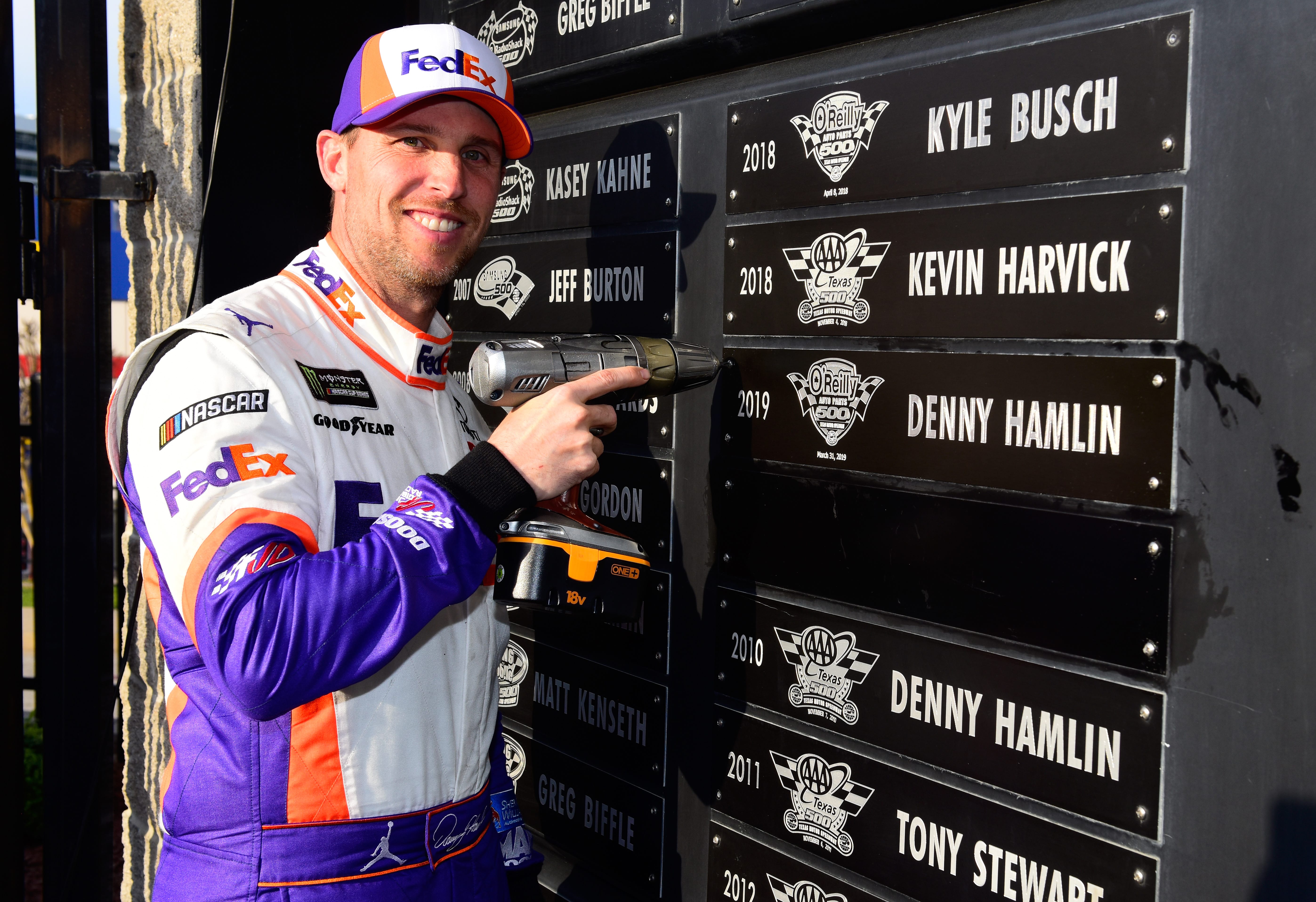 FORT WORTH, TX - MARCH 31:  Denny Hamlin, driver of the #11 FedEx Office Toyota, affixes his name plate to 