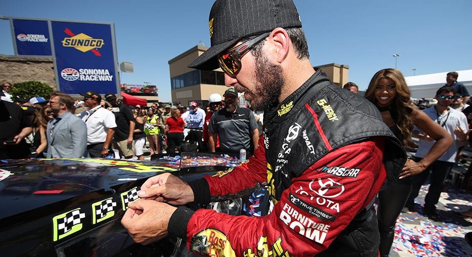 SONOMA, CA - JUNE 24: Martin Truex Jr., driver of the #78 5-hour ENERGY/Bass Pro Shops Toyota, celebrates in victory lane by placing the winner's sticker on his car after winning the Monster Energy NASCAR Cup Series Toyota/Save Mart 350 at Sonoma Raceway on June 24, 2018 in Sonoma, California. (Photo by Chris Graythen/Getty Images) | Getty Images