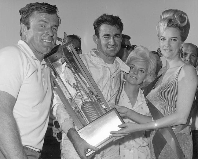 MACON, GA - NOVEMBER 12, 1967:  Middle Georgia Raceway, near Macon, hosted many top notch stock car events on its half-mile, paved surface. Here Bobby Allison and wife Judy (right of Bobby) enjoy a win at the Central Georgia track. Holman-Moody crew chief Fred Lorenzen (left) appreciates the win as well.  (Photo by ISC Archives via Getty Images)
