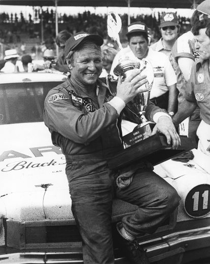 DARLINGTON, SC — September 2, 1974: Cale Yarborough holds his trophy in victory lane at Darlington Raceway after winning the Southern 500 NASCAR Cup race. (Photo by ISC Images & Archives via Getty Images)