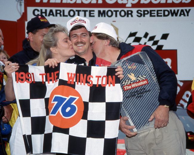 CONCORD, NC - MAY 19: Driver Davey Allison gets a kiss from Miss Winston and car owner Robert Yates after winning The Winston VII race on May 19, 1991 at tha Charlotte Motor Speedway in Concord, North Carolina. (Photo by Dozier Mobley/Getty Images)
