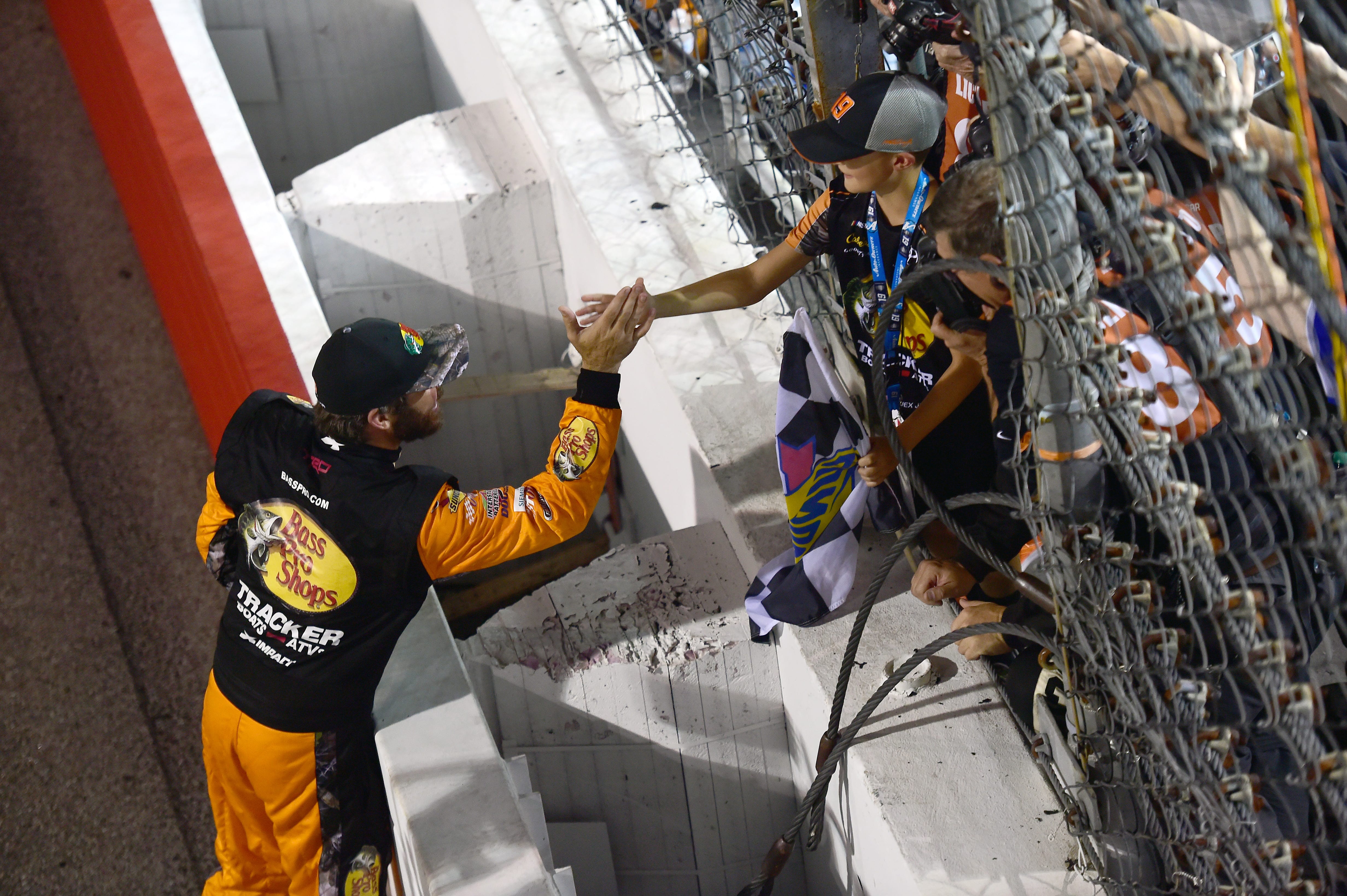 RICHMOND, VIRGINIA - SEPTEMBER 21: Martin Truex Jr., driver of the #19 Bass Pro Shops Toyota, celebrates and hands the checkered flag to a young fan after winning the Monster Energy NASCAR Cup Series Federated Auto Parts 400 at Richmond Raceway on September 21, 2019 in Richmond, Virginia. (Photo by Jared C. Tilton/Getty Images) | Getty Images