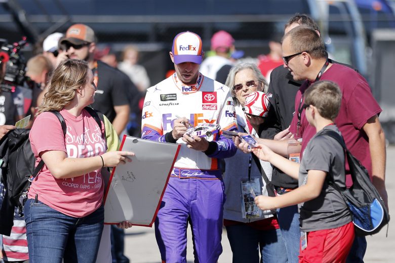 KANSAS CITY, KANSAS - OCTOBER 18: Denny Hamlin, driver of the #11 FedEx Office Toyota, signs autographs for fans in the garage area during practice for the Monster Energy NASCAR Cup Series Hollywood Casino 400 at Kansas Speedway on October 18, 2019 in Kansas City, Kansas. (Photo by Brian Lawdermilk/Getty Images) | Getty Images