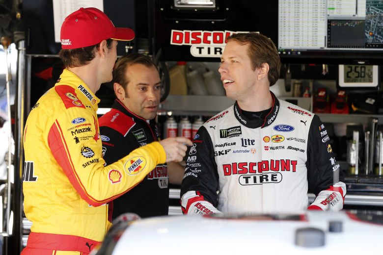 KANSAS CITY, KANSAS - OCTOBER 18: Joey Logano, driver of the #22 Shell Pennzoil Ford, speaks with teammate Brad Keselowski, driver of the #2 Discount Tire Ford, in the garage area during practice for the Monster Energy NASCAR Cup Series Hollywood Casino 400 at Kansas Speedway on October 18, 2019 in Kansas City, Kansas. (Photo by Brian Lawdermilk/Getty Images) | Getty Images