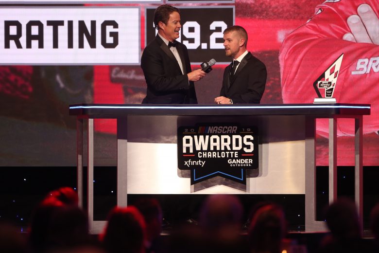 CHARLOTTE, NORTH CAROLINA - NOVEMBER 22: NASCAR driver Justin Allgaier speaks as Dave Burns looks on during the NASCAR Xfinity Series and NASCAR Gander Outdoors Truck Series Championship Banquet at Charlotte Convention Center on November 22, 2019 in Charlotte, North Carolina. (Photo by Brian Lawdermilk/Getty Images) | Getty Images