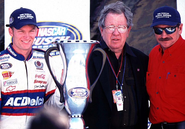 Newly crowned NASCAR Busch Series Champion Dale Earnhardt, Jr. (left) poses with his trophy and NASCAR President Bill France Jr. (center) and his father Dale Earnhardt Sr. at Homestead, Florida November 13, 1999. (Photo by Brian Cleary)