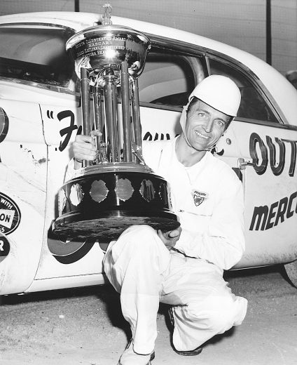 1955: Tim Flock holds the Sports Illustrated NASCAR Cup Series championship trophy, which he earned in 1955. Flock drove the Karl Kiekhaefer Chrysler during the season in 41 starts and 18 wins (32 top five place finishes). (Photo by ISC Archives/CQ-Roll Call Group via Getty Images)