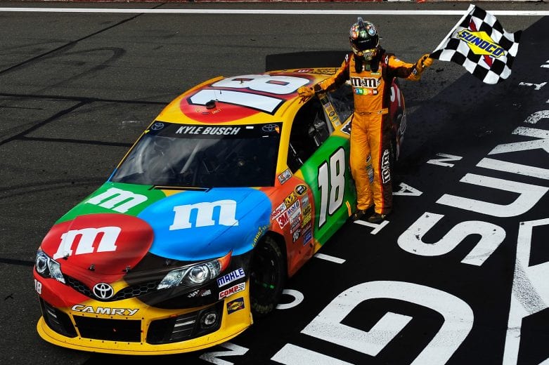 WATKINS GLEN, NY - AUGUST 11: Kyle Busch, driver of the #18 M&M's Toyota, celebrates with the checkered flag after winning the NASCAR Sprint Cup Series Cheez-It 355 at The Glen at Watkins Glen International on August 11, 2013 in Watkins Glen, New York. (Photo by Jared C. Tilton/NASCAR via Getty Images)