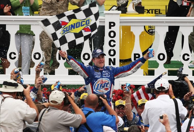 LONG POND, PA - AUGUST 05:  Kurt Busch, driver of the #2 Miller Lite Dodge, waves the checkered flag as he celebrates with his crew in victory lane after winning the NASCAR Nextel Cup Series Pennsylvania 500 at Pocono Raceway on August 5, 2007 in Long Pond, Pennsylvania.  (Photo by Al Bello/Getty Images) | Getty Images