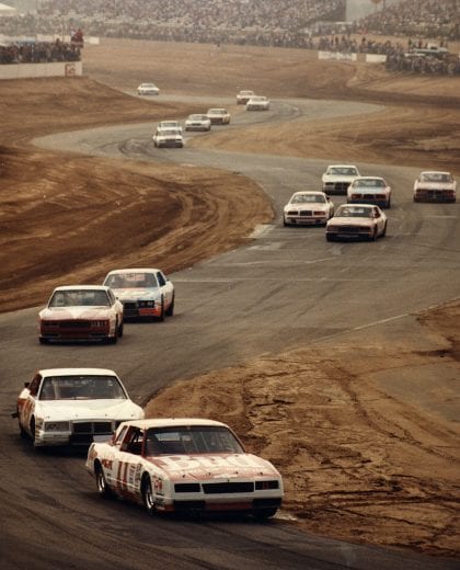 RIVERSIDE, CA — Mid-1980s:  Darrell Waltrip (No. 11) leads the field through the twists and turns of Riverside International Raceway during a NASCAR Cup race.  Waltrip scored five total Cup victories at Riverside, but just one while driving the Budweiser Chevrolet for car owner Junior Johnson.  However, it was the best race he could have won there as he took the checker first in his sponsor’s Bud 400 on June 1, 1986.  (Photo by ISC Images & Archives via Getty Images)
