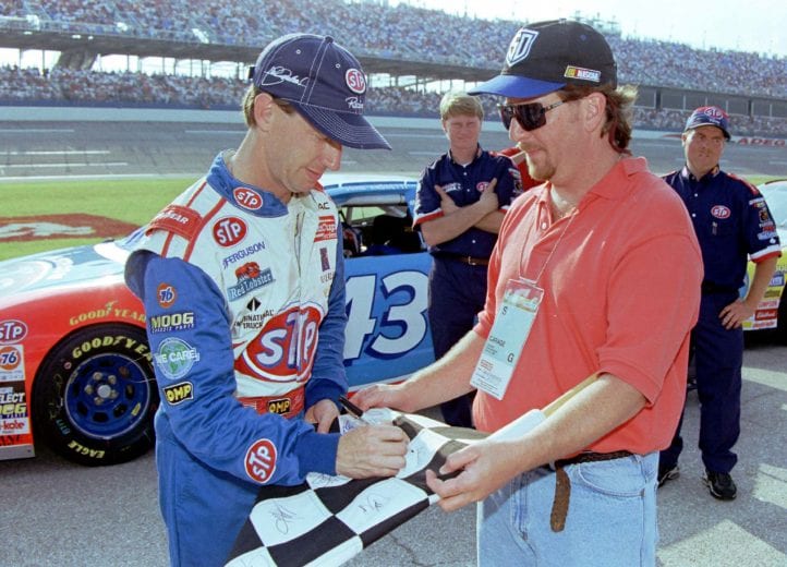 TALLADEGA, AL - APRIL 23:  John Andrett driver of the #43 STP Pontiac owned by Richard Petty signs an autograph for a fan as he waits to qualify for the Winston Cup Diehard 500 on April 23, 1999 at the Talladega Superspeedway at Talladega, Alabama.  (Photo by Brian Cleary/Getty Images)