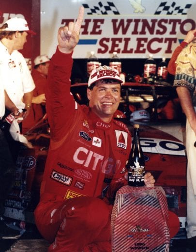 CONCORD, NC - MAY 20:  Driver Michael Waltrip smiles with trophy and champagne after winning the 1996 The Winston Select race on May 20, 1996 at the Charlotte Motor Speedway in Concord, North Carolina. (Photo by Dozier Mobley/Getty Images)