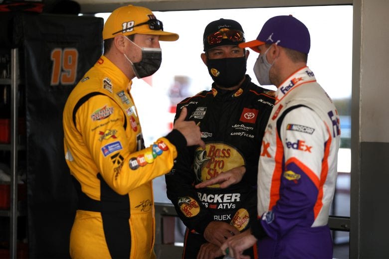 DAYTONA BEACH, FLORIDA - FEBRUARY 10: Kyle Busch, driver of the #18 M&M's Toyota, Martin Truex Jr., driver of the #19 Bass Pro Shops Toyota, and Denny Hamlin, driver of the #11 FedEx Express Toyota, talk in the garage area during practice for the NASCAR Cup Series 63rd Annual Daytona 500 at Daytona International Speedway on February 10, 2021 in Daytona Beach, Florida. (Photo by Chris Graythen/Getty Images) | Getty Images