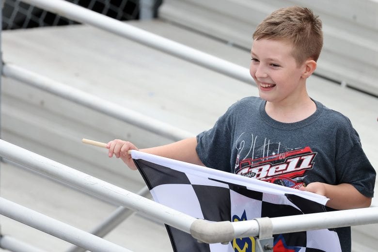 LOUDON, NEW HAMPSHIRE - JULY 17: A young NASCAR fans smiles after receiving the checkered flag from Christopher Bell, driver of the #54 DEWALT Toyota, after Bell won the NASCAR Xfinity Series Ambetter Get Vaccinated 200 at New Hampshire Motor Speedway on July 17, 2021 in Loudon, New Hampshire. (Photo by James Gilbert/Getty Images) | Getty Images