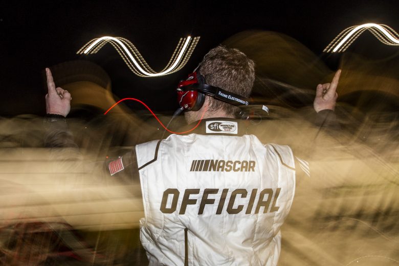 An official signals for drivers to start their engines during the New Smyrna Visitors Bureau 200 for the NASCAR Whelen Modified Tour during night 2 of the World Series of Asphalt Stock Car Racing at New Smyrna Speedway in New Smyrna, Florida on February 12, 2022. (Adam Glanzman/NASCAR)