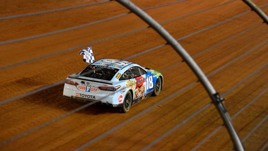 BRISTOL, TENNESSEE - APRIL 17: Kyle Busch, driver of the #18 Mars Crunchy Cookie Toyota, celebrates with the checkered flag after winning the NASCAR Cup Series Food City Dirt Race at Bristol Motor Speedway on April 17, 2022 in Bristol, Tennessee. (Photo by Logan Riely/Getty Images) | Getty Images