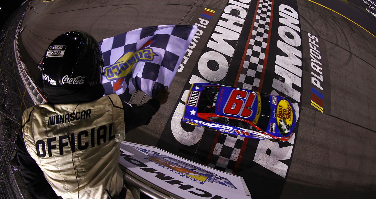 Truex crosses the finish line as the NASCAR official waves the checkered flag.