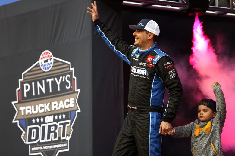 BRISTOL, TENNESSEE - APRIL 16: Stewart Friesen, driver of the #52 Halmar International Toyota, and son Parker wave to fans as th walks onstage during driver intros prior to the NASCAR Camping World Truck Series Pinty's Truck Race on Dirt at Bristol Motor Speedway on April 16, 2022 in Bristol, Tennessee. (Photo by Chris Graythen/Getty Images) | Getty Images
