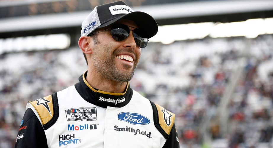 Aric Almirola smiles with Smithfield hat on and Smithfield firesuit