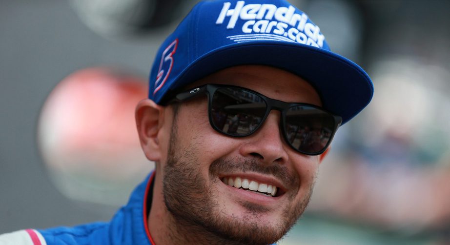 Kyle Larson smiles with sunglasses and Hendrick hat on