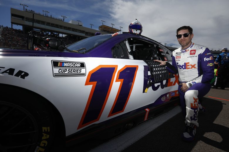 Denny Hamlin kneels as he poses for a photo alongside the No. 11 Toyota before the Ruoff Mortgage 500 at Phoenix Raceway