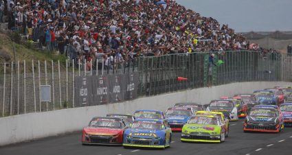 Drivers race past fan-filled grandstands in a NASCAR Mexico Series race.