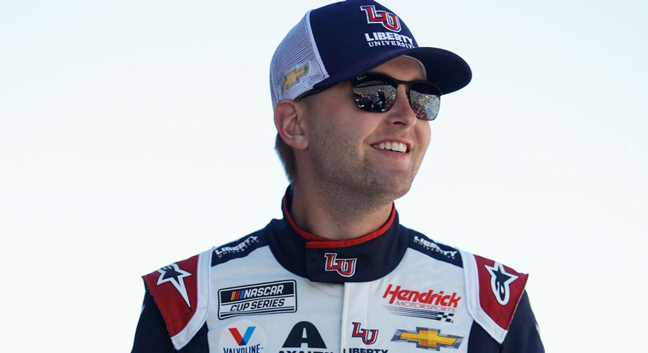 William Byron smiling in sunglasses and a Liberty University hat