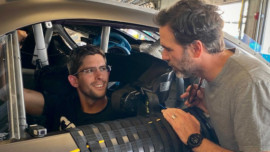 Jimmie Johnson leans in to chat with four-time IMSA champion Jordan Taylor in the Daytona International Speedway garage