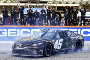 Tyler Reddick performs a burnout in his No. 45 car in front of crew members after winning at COTA