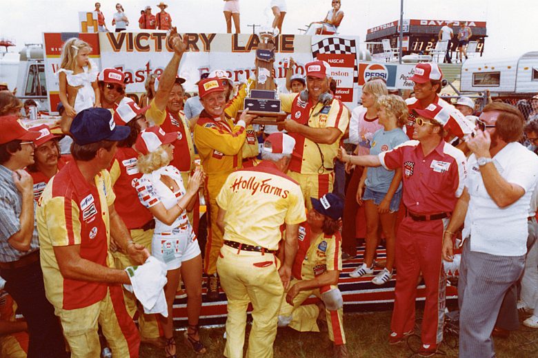 DAYTONA BEACH, FL — July 4, 1976: Driver Cale Yarborough (L) and car owner Junior Johnson (R) hold their trophy in victory lane at Daytona International Speedway after winning the Firecracker 400 NASCAR Cup race. (Photo by ISC Images & Archives via Getty Images)
