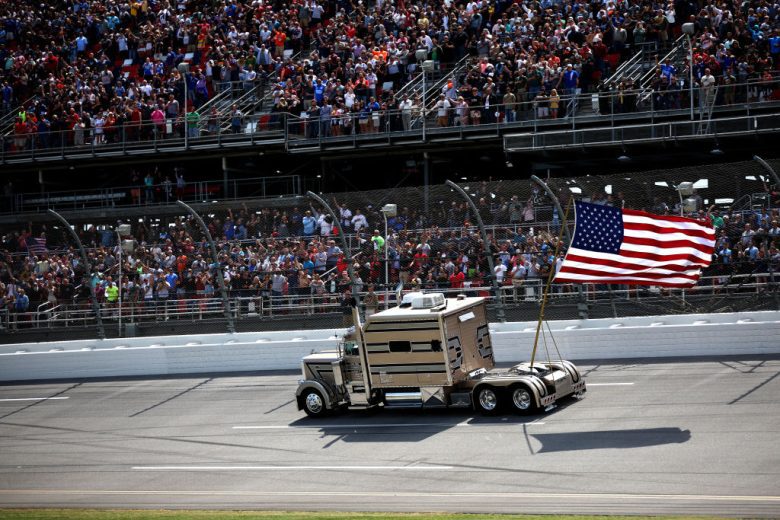 A truck carrying the American flag drives by