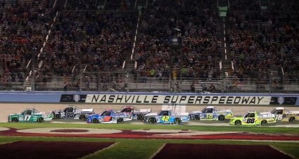 NASCAR Craftsman Truck Series trucks race across start/finish line at Nashville Superspeedway.