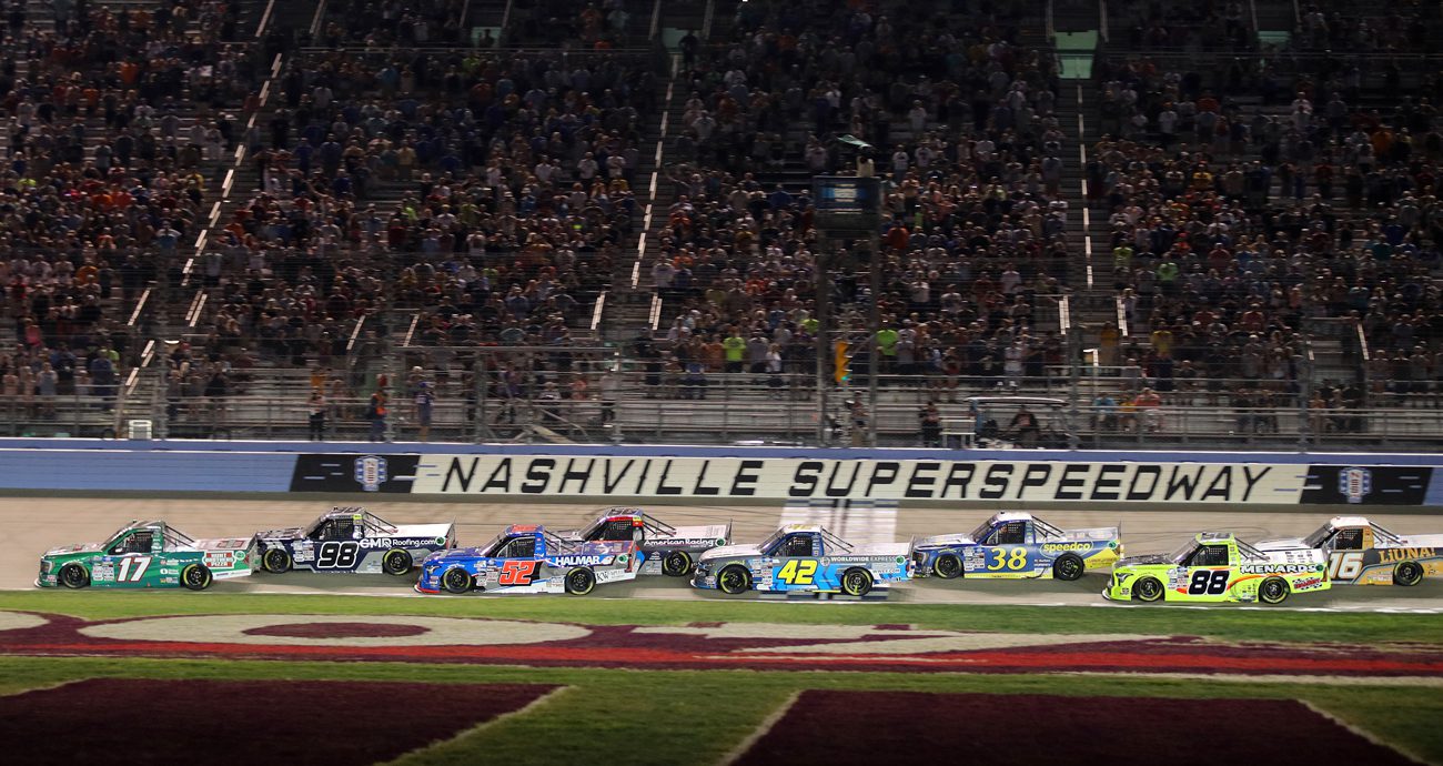 NASCAR Craftsman Truck Series trucks race across start/finish line at Nashville Superspeedway.