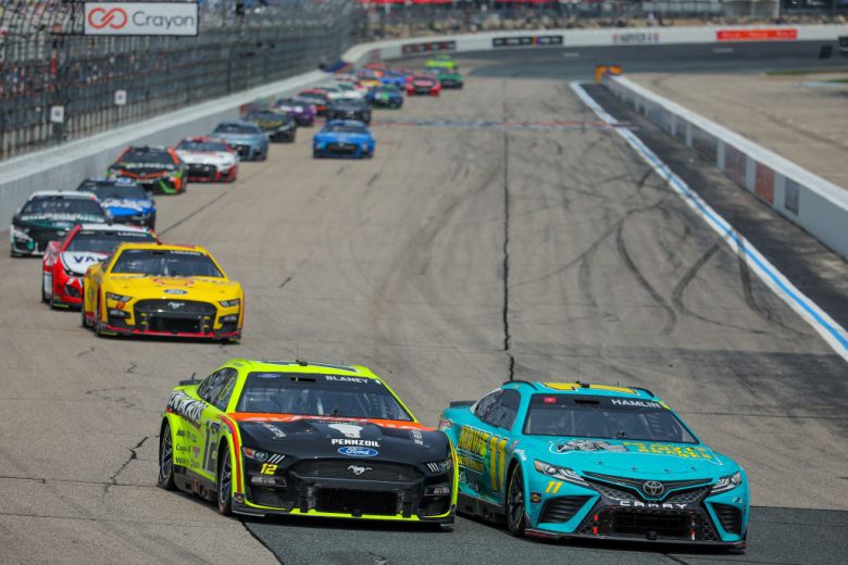 NASCAR Cup Series cars round a turn at New Hampshire Motor Speedway.