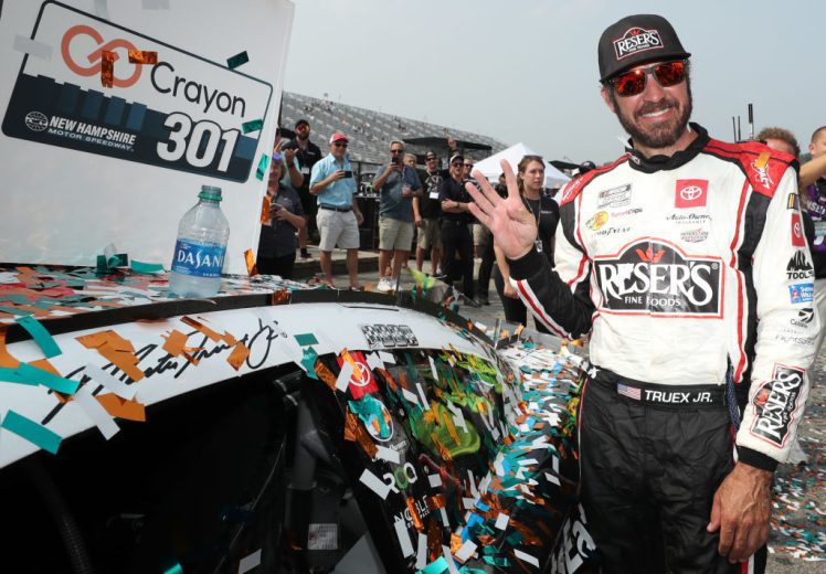 Martin Truex Jr. poses next to No. 19 car after winning at New Hampshire Motor Speedway.