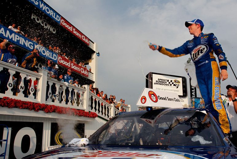 Brad Keselowski stands on his No. 2 car, flinging a sports drink onto his team in Victory Lane