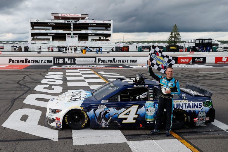 Kevin Harvick waves the checkered flag, his car parked at Victory Lane