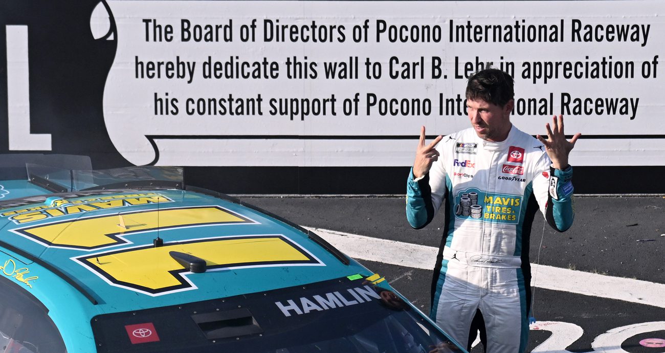 Denny Hamlin poses for a photo in Victory Lane and puts up seven fingers, signifying the number of NASCAR Cup Series wins he has at Pocono Raceway.