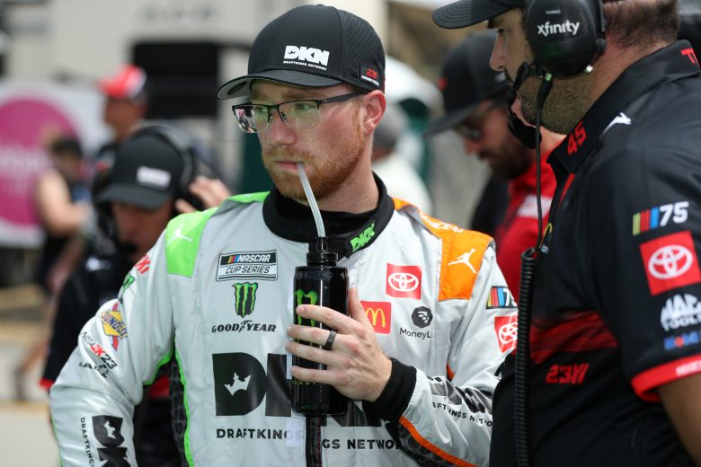 Tyler Reddick stands on pit road drinking from a sports bottle